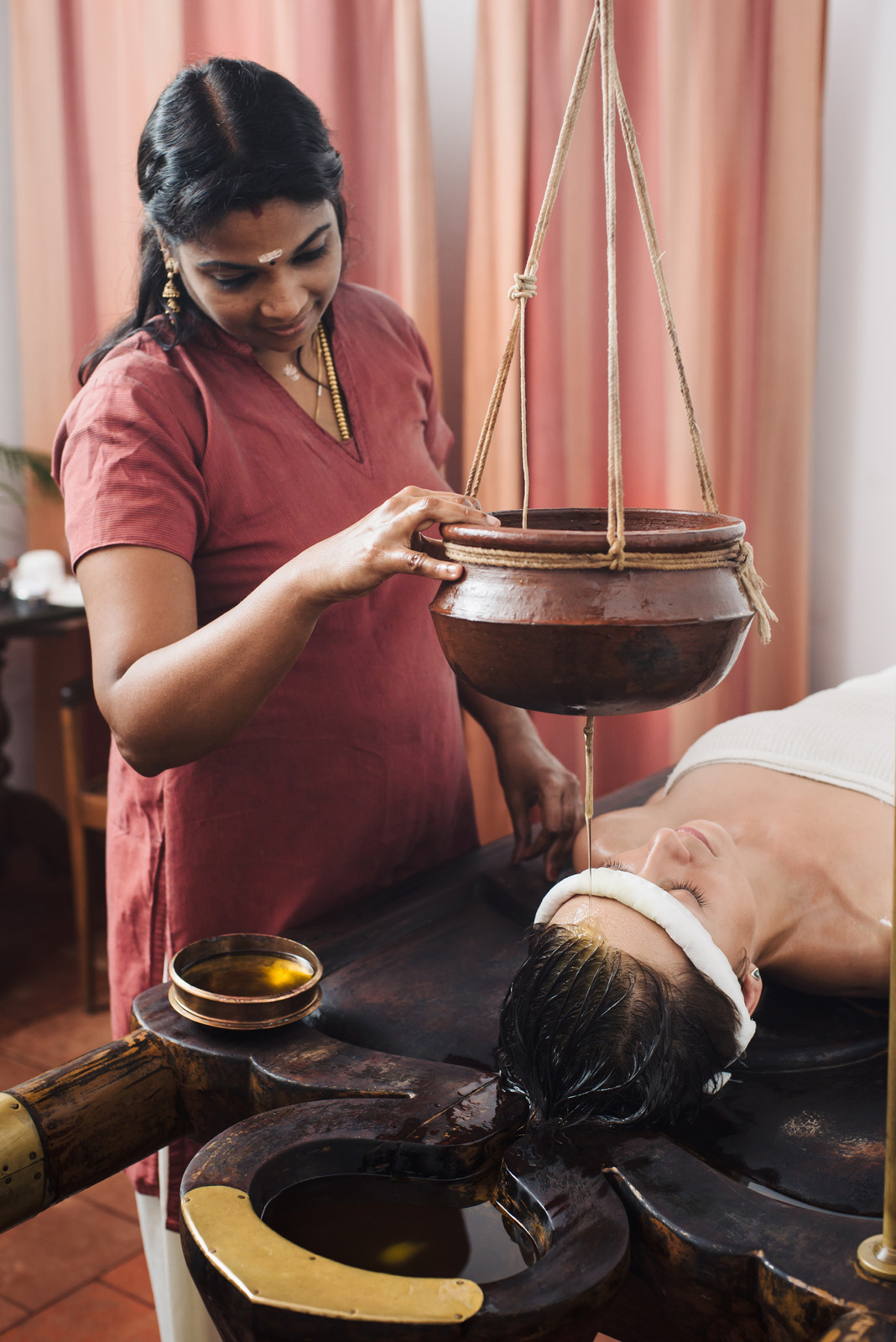 Ayurvedic therapist performing Shirodhara treatment on a woman in Hyderabad to improve quality of life through holistic MS therapy.